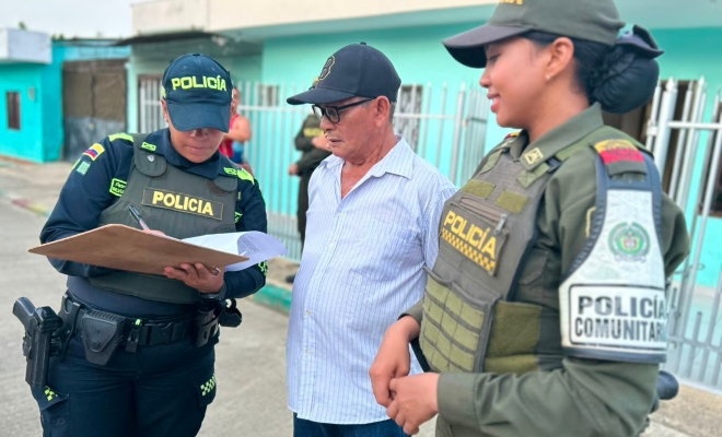 Dos funcionarias policiales junto a un ciudadano firmando una planilla
