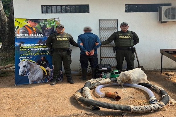Dos policías custodian a un hombre capturado junto a una máquina incautada