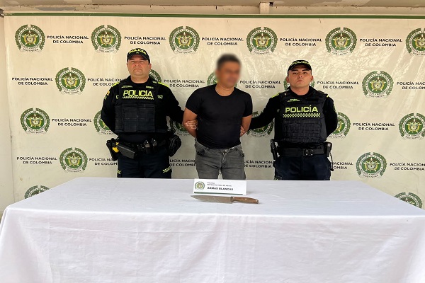 Dos polic&iacute;as junto a un hombre capturado y un arma blanca incautada