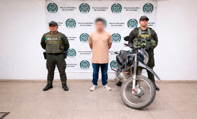 Un ciudadano capturado esposado con dos policías a su lado y una motocicleta recuperada 