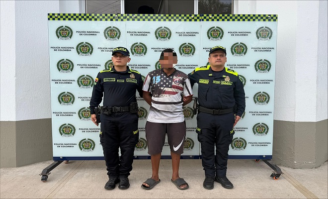 Un ciudadano masculino capturado por orden judicial con dos funcionarios de la Policía Nacional, uno de cada lado brindando seguridad