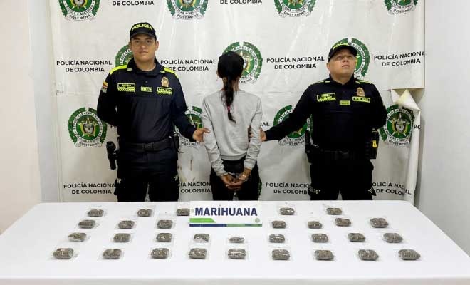 Mujer capturada en medio de dos policías, al frente sustancia incautada
