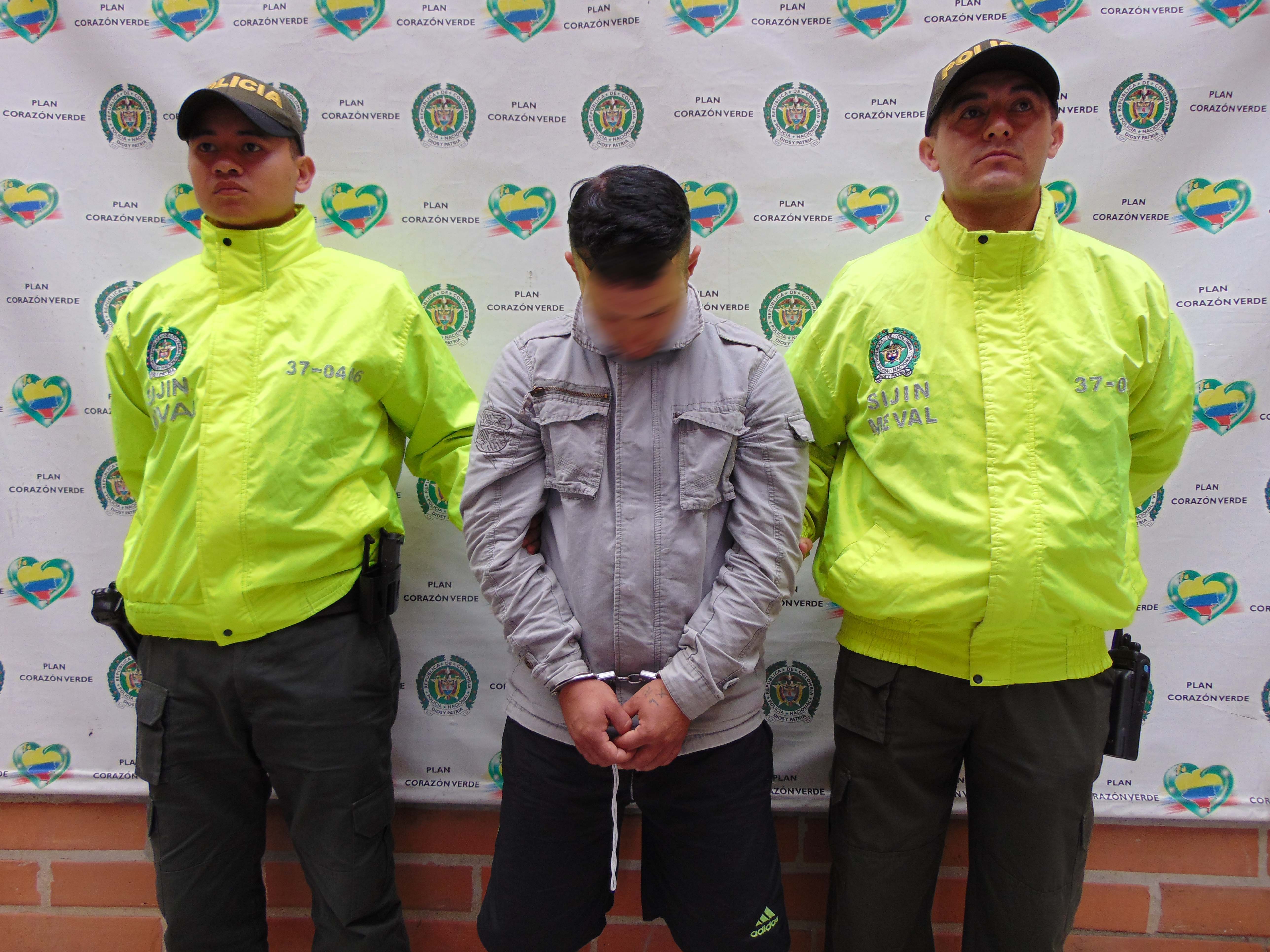 Dos policías custodian un hombre capturado quien se encuentra esposado