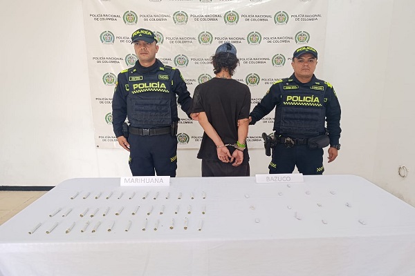 Dos Policías, un capturado y mesa con estupefacientes
