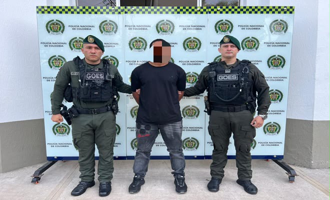 Una persona de sexo masculino capturada por el delito de homicidio agravado y concierto  para delinquir agravado, acompañado de dos uniformados al costado brindando seguridad.