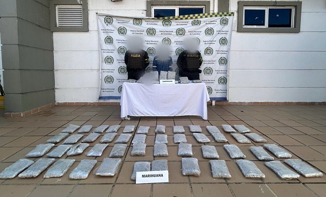 Sustancia marihuana distribuida en el piso, donde también hay dos policías junto a la persona capturada 