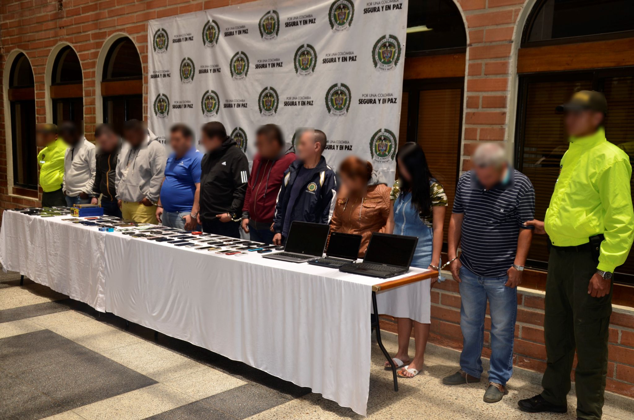 Policías de la Sijin custodian a capturados en Medellín por tráfico de celulares hurtados