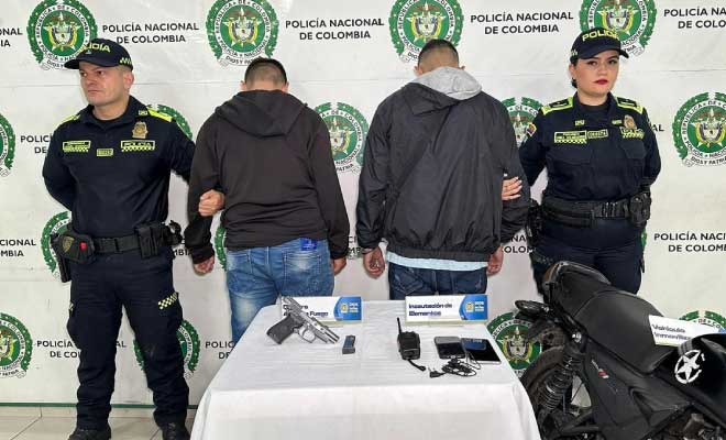 Hombres capturados en medio de dos Policías, en frente elementos incautados