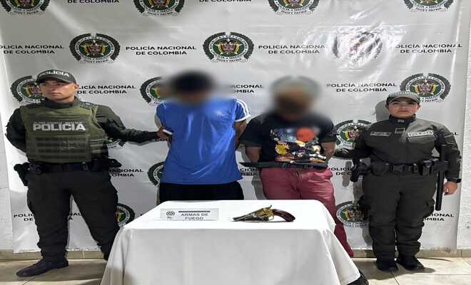 Dos personas capturadas esposadas con dos policías en cada lado respectivamente 