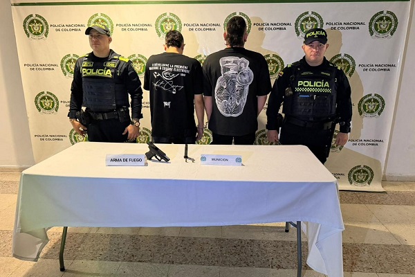 Dos Polic&iacute;as, dos capturados, mesa con arma de fuego