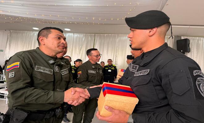 Oficial de la Policía entregando reconocimiento a instructor del curso OTU