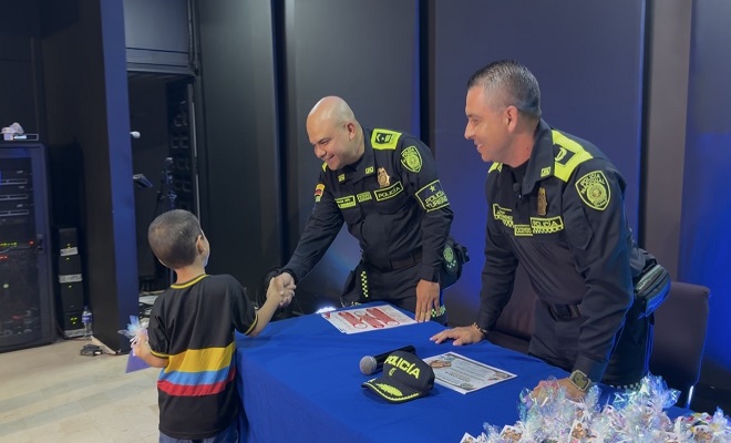 Dos uniformados de la Policía Nacional saludando de la mano a un niño