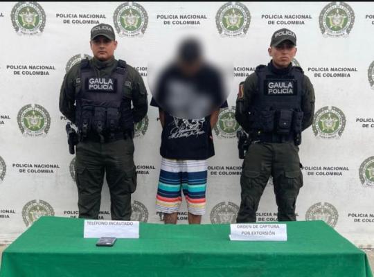 dos policías al lado de un hombre capturado por extorsión