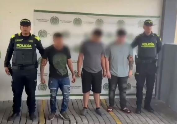 dos policias al lado de tres hombres capturados