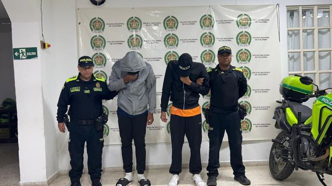 Dos policías al lado de dos hombres capturados