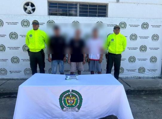 dos policías al lado de tres hombres capturados