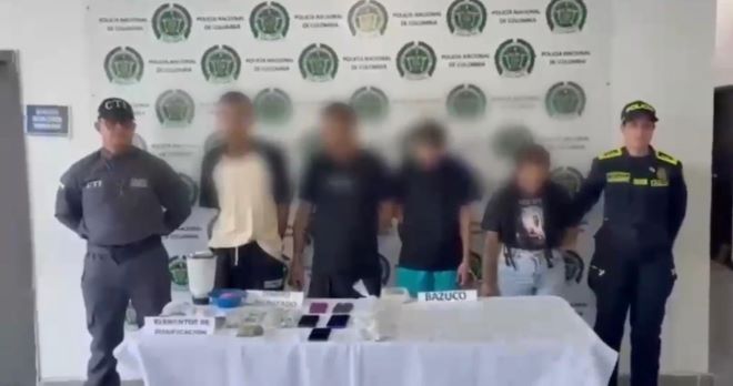dos policías al lado de tres hombres capturados una mujer