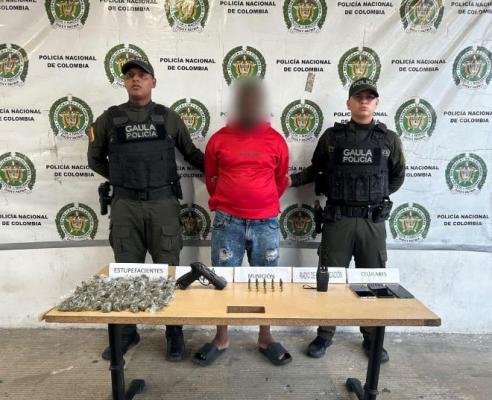 dos policías al lado de un hombre capturado con material incautado