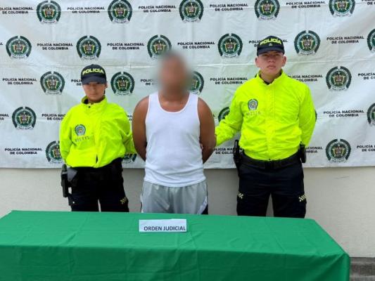 dos policías al lado de un hombre capturado por orden judicial
