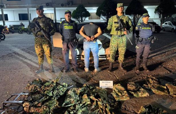 dos policías dos soldados al lado de un hombre capturado con material de intendencia militar