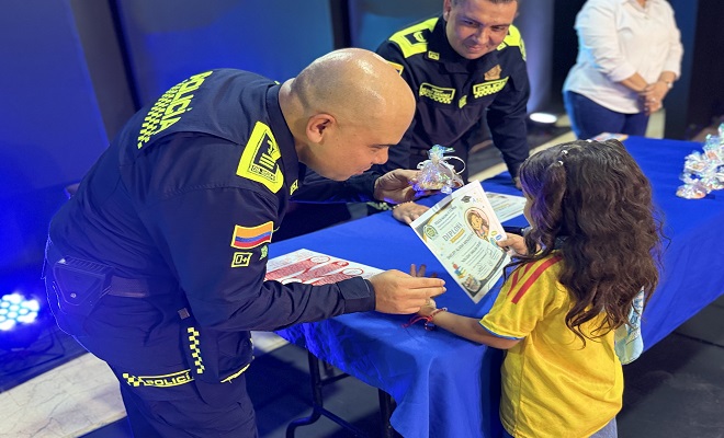Uniformado de la Policía Nacional entregando diploma a una niña por su participación en el programa 