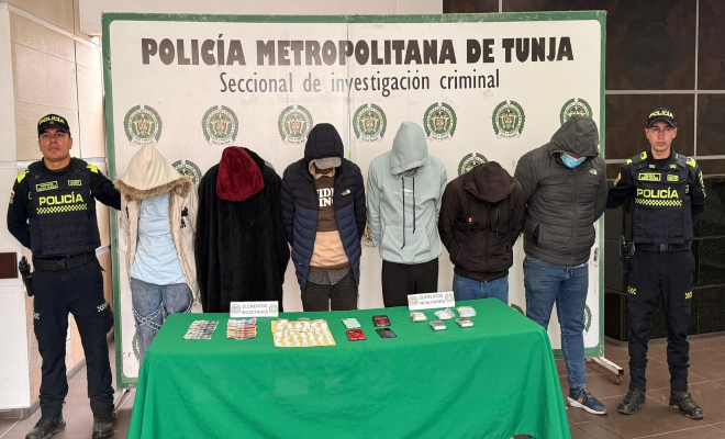 Seis personas capturadas a los lados dos policías y una mesa con un mantel verde y elementos incautados  