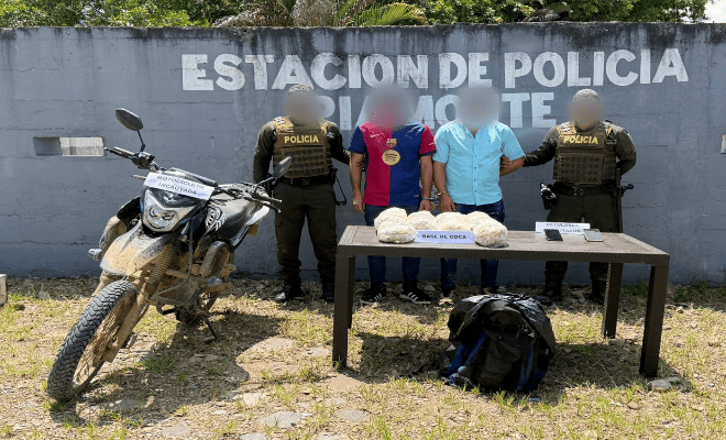 Dos policías, Dos capturados, estupefacientes incautados encima de una mesa y una motocicleta recuperada