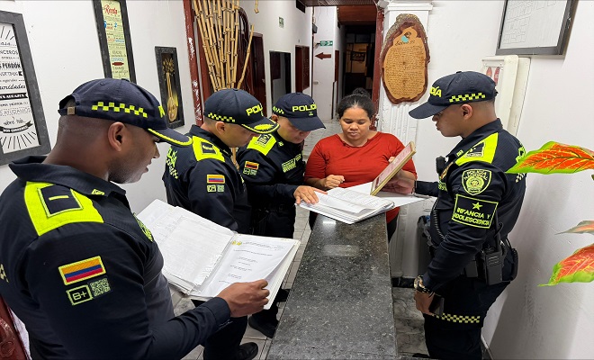4 funcionarios de la Policía Nacional en compañía de la recepcionista de un hotel, verificando el cumplimiento a la documentación exigida a cada establecimiento  