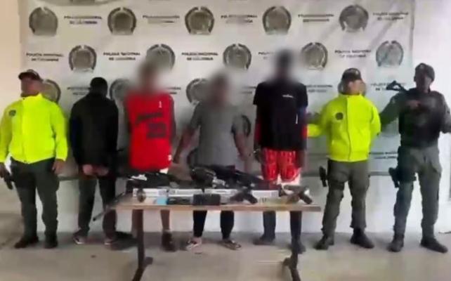 tres polic&iacute;as al lado de cuatro hombres capturados