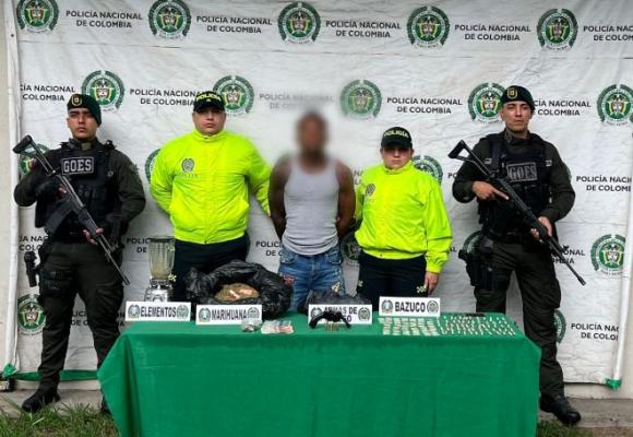 La policía nacional al lado de un hombre capturado con material incautado