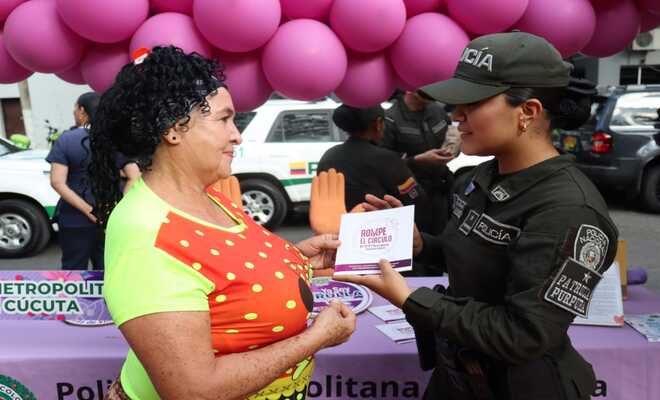 Uniformada de la Patrulla Púrpura socializando la línea 155 a una ciudadana.