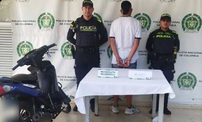Hombre capturado en medio de dos Policías en frente motocicleta recuperada