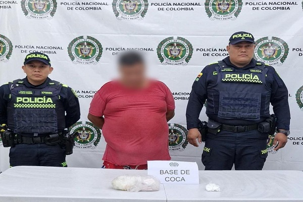 Dos polic&iacute;as junto a un hombre capturado y sustancia estupefaciente incautada
