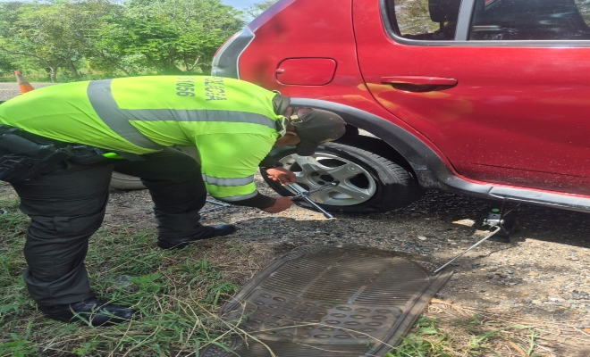 Uniformado de la seccional de transito y transporte ayudando a soltar la llanta de un vehículo