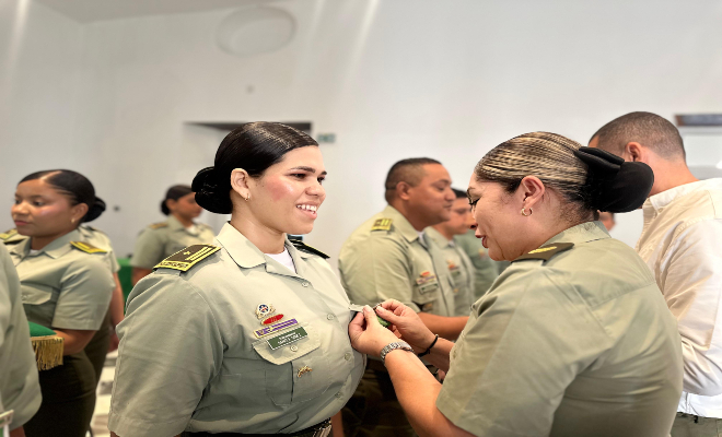 coronel poniendo una condecoración a una uniformada por su buen comportamiento y su destacamiento