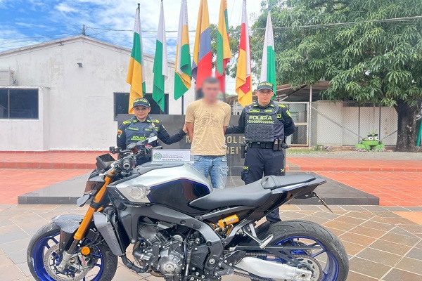 Dos Policías custodian a un capturado y motocicleta recuperada