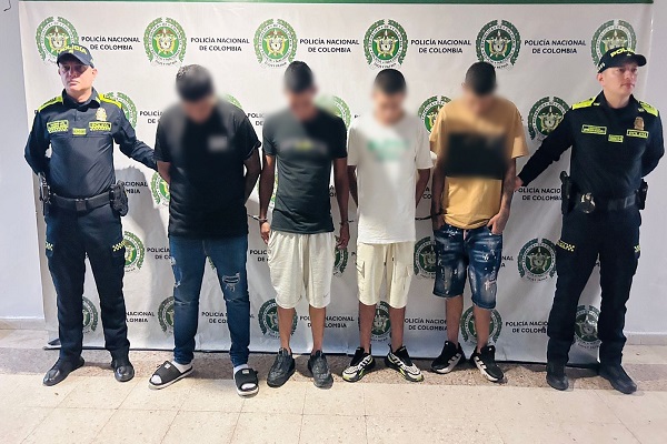 Dos uniformados custodian a cuatro hombres capturados por su presunta participaci&oacute;n en actividades de tr&aacute;fico local de estupefacientes 