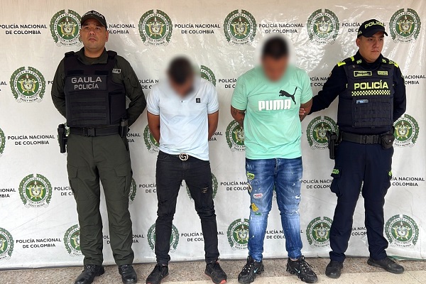 Dos policías custodian a dos hombres capturados señalados de presunto secuestro