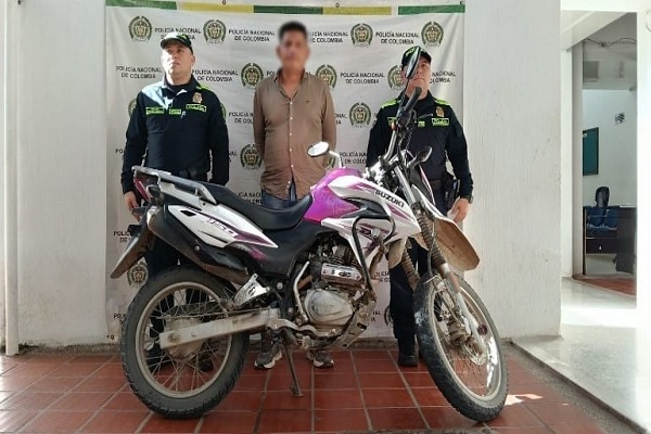 Dos policías presentan al capturado y la motocicleta recuperada