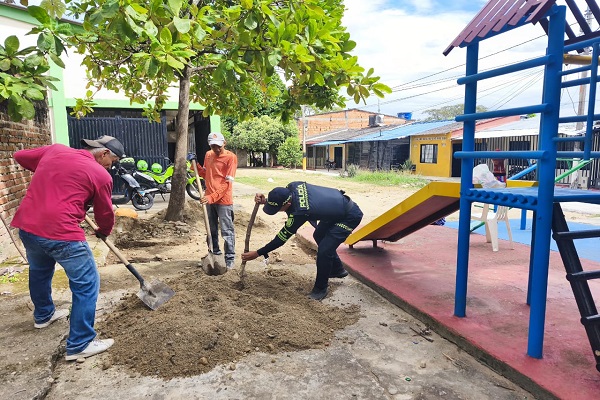 Un policía y dos ciudadanos realizan labores de cementación para recuperar un parque
