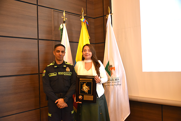 Entrega de reconocimiento a participante durante evento académico.
