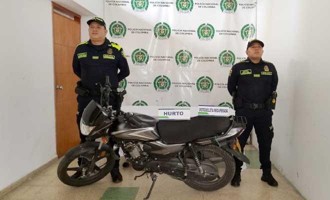 Dos policías, en frente motocicleta recuperada
