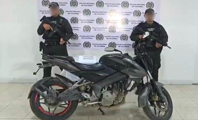 Dos polic&iacute;as frente a una moto recuperada