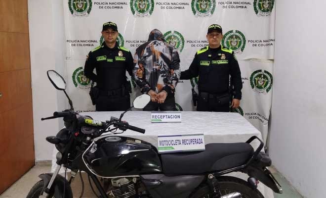 Hombre capturado en medio de dos Policías, enfrente motocicleta recuperada