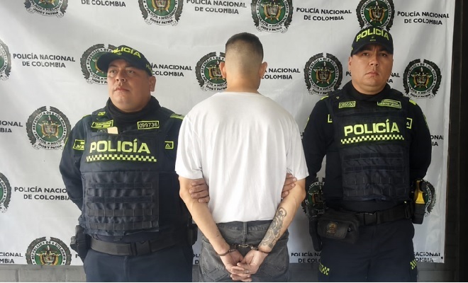 hombre_de_camiseta_blanca_capturado_en_medio_de_dos_policías
